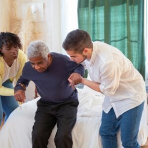 An elderly man receiving assistance from caregivers in a cozy home environment.